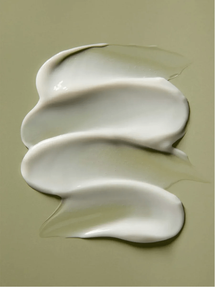 Swirls of cream from AROMATICA Rosemary Hair Thickening Conditioner on a neutral background.