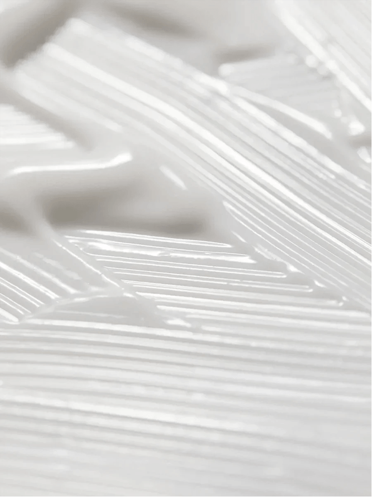 Close-up of a creamy texture of AROMATICA Rosemary Hair Thickening Conditioner on a surface.