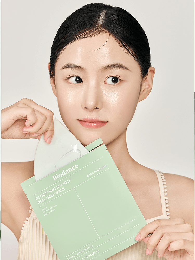 Model applying BIODANCE Refreshing Sea Kelp Real Deep Mask on her face, showcasing skincare routine with mask pack.