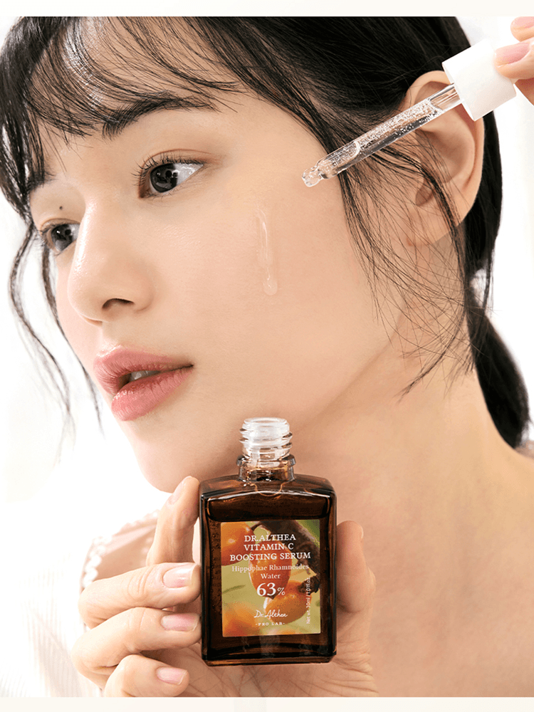 Woman applying Dr.Althea Vitamin C Boosting Serum 30ml on her face with a dropper for healthy glowing skin.
