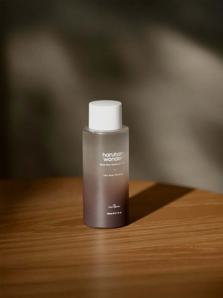 HARUHARU WONDER Black Rice Hyaluronic Toner 150ml on a wooden surface with soft lighting.