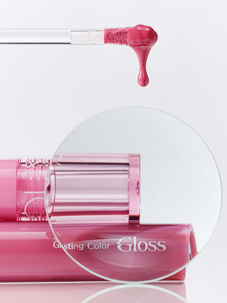 rom&nd Glasting Color Gloss 4g applicator with a drop of pink gloss and the product tube in the background.